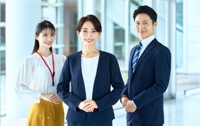 男性社員1名、女性社員2名が笑顔でこちらを向いている
